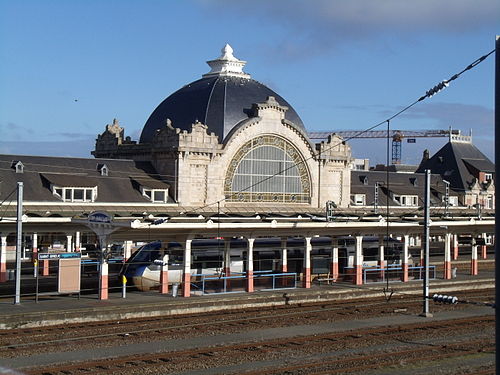 大きなドーム型の建物とプラットフォームに高速列車がある駅