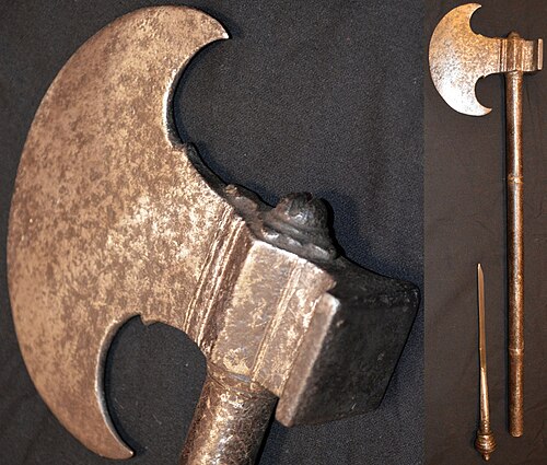 シンド地方のタバル戦斧、18世紀後半またはそれ以前。三日月形の刃先は長さ12cm（5インチ）、刃の反対側に四角いハンマーが付いている。柄は長さ55cm（22インチ）の鋼鉄製で、柄の先端をねじって外すと、12cm（5インチ）の細身の刃が現れる。刃先と柄には強い古色があり、彫刻の痕跡が見られる。
