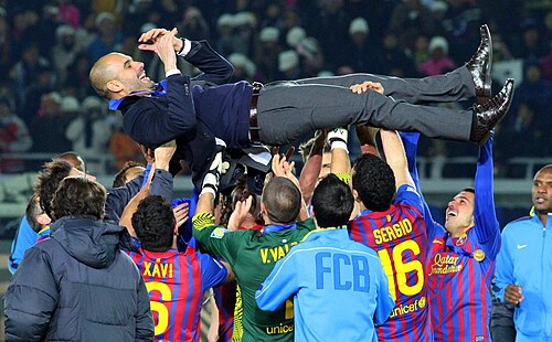 写真撮影当時、FCバルセロナに所属していたサッカー選手たちが、2度目のFIFAクラブワールドカップ優勝後、監督を担ぎ上げている様子。