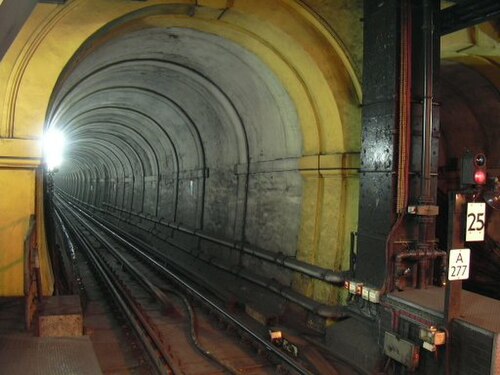 明るい白色光に照らされた、一本の線路がある狭い鉄道トンネル