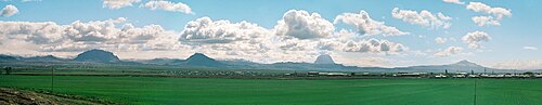 遠くに孤立した山々が連なる広大な緑の平原