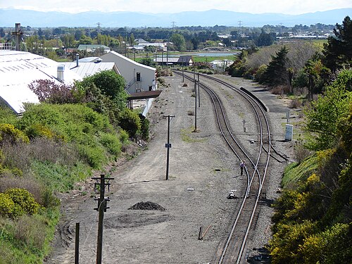 かつてのヒースコート駅の敷地の全景。駅の唯一の名残であるプラットホームが今も見ることができます。メイン サウス ラインは、この写真が撮影された場所の下にあるリトルトン鉄道トンネルに消えていきます。