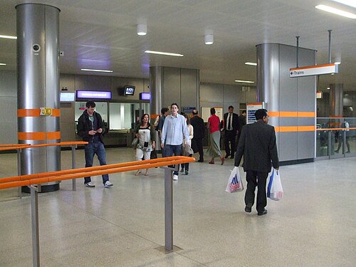 反射する銀色の金属で覆われたダルストン ジャンクション駅のコンコース。駅の周囲を人が行き交っています。