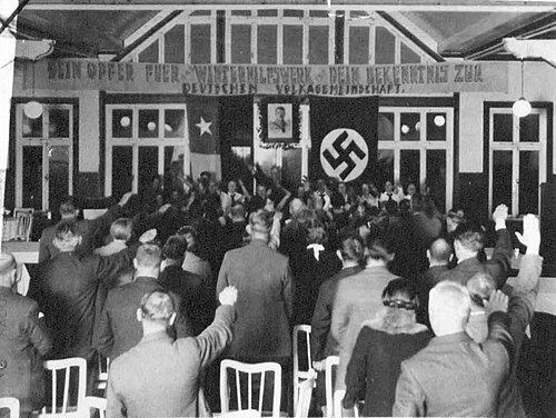 ナチス式敬礼をする人々を写した白黒写真。正面からナチスが敬礼を返している。
