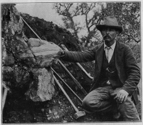 ウィリアム E. ヒデンは、1903 年にバリンジャー ヒルに設置された 73 ポンド (33 kg) のガドリン石の塊の隣にいます。