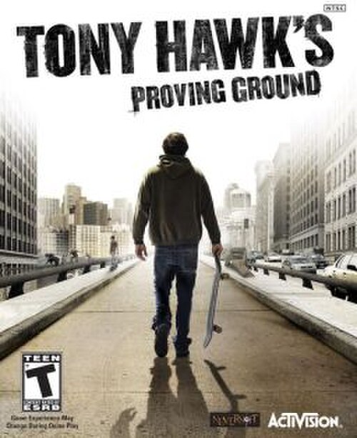 ジャケットを着た男性がスケートボードを持って歩いています。上部には「Tony Hawk's Proving Ground」という文字が大文字で表示されています。