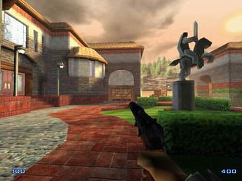 ゲームの初期開発バージョンのスクリーンショット。画像には、建物の隣の中庭で銃を持っている男性プレイヤー キャラクターが写っています。