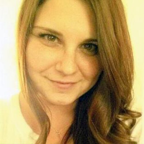 30代前半の白人女性。長くまっすぐな茶色の髪で、カメラに向かって微笑んでいる。