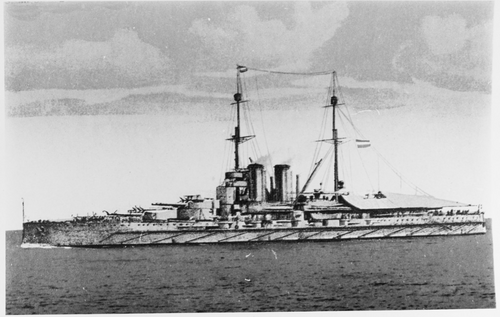 巨大な戦艦が水面を進んでいます。船の煙突から少量の煙が出ているのが見えます。