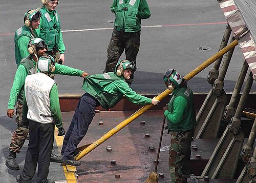 緑色のシャツを着ている人は、一般的に航空機または機器の整備担当者です。