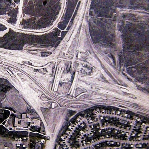 建設中の大型高速道路インターチェンジの鳥瞰図。いくつかの橋は完成しているが、橋の間を迂回する水平に交差する 1 本の高速道路を除いて、舗装されていない。