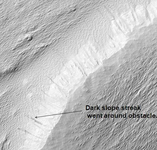 HiRISE が撮影したニコルソンクレーター中央丘。画像をクリックすると、障害物によって迂回された暗い斜面の筋が見えます。